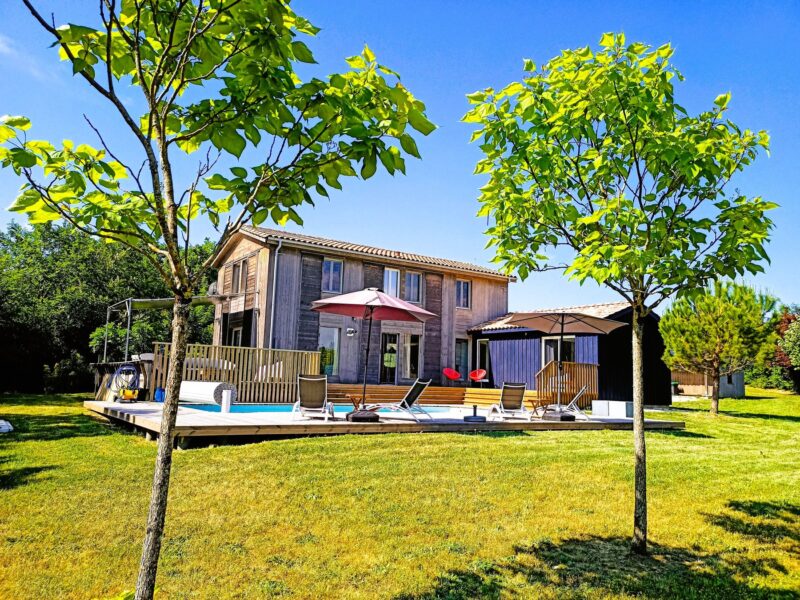 Jardin arboré et parasols devant la maison en bois