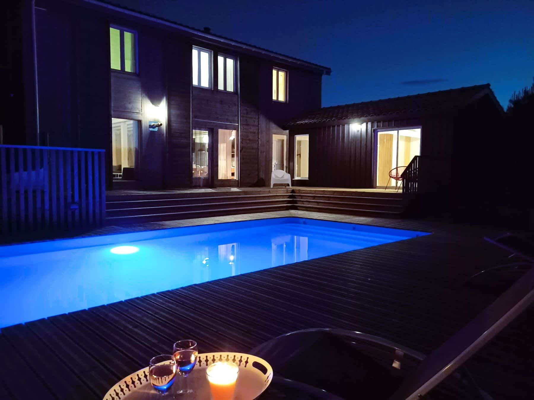 La maison et sa piscine éclairée à la tombée de la nuit, gîte Les Terrasses