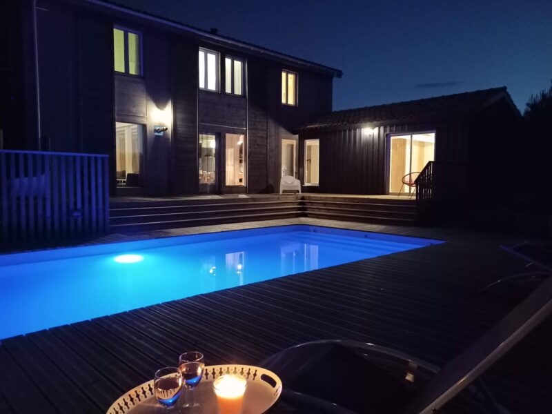 Piscine éclairée et maison à la nuit tombée