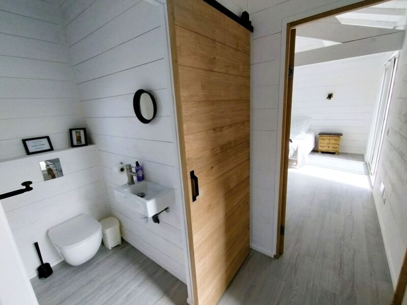 Salle d'eau avec lavabo, WC et porte coulissante en bois, Maison Les Terrasses