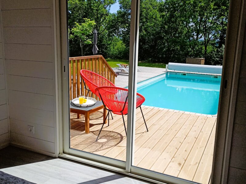 Baie vitrée du séjour ouverte sur la terrasse et la piscine chauffée
