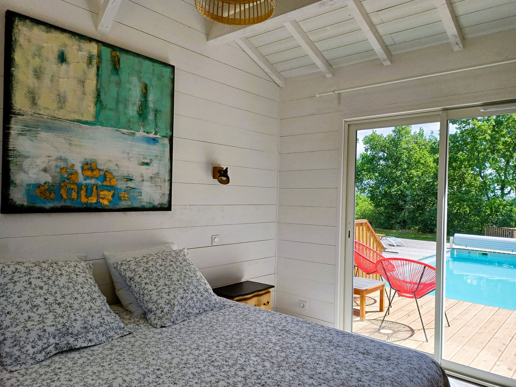Chambre avec lit double et accès direct à la terrasse et à la piscine